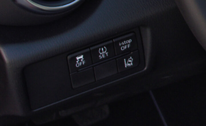 ND MX-5 lower dash switch panel left of the steering wheel: DSC OFF button with skid-mark car icon, TPMS SET, i-stop OFF, and the lane departure warning off button with a car crossing a lane line