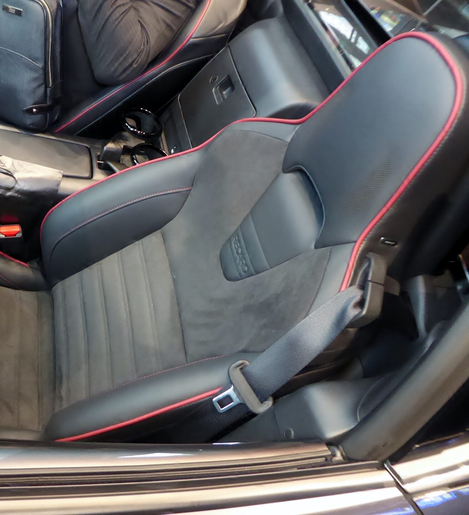 Recaro sport seat in an ND MX-5 with the RECARO logo embossed on the seatback, suede center panel, and red piping